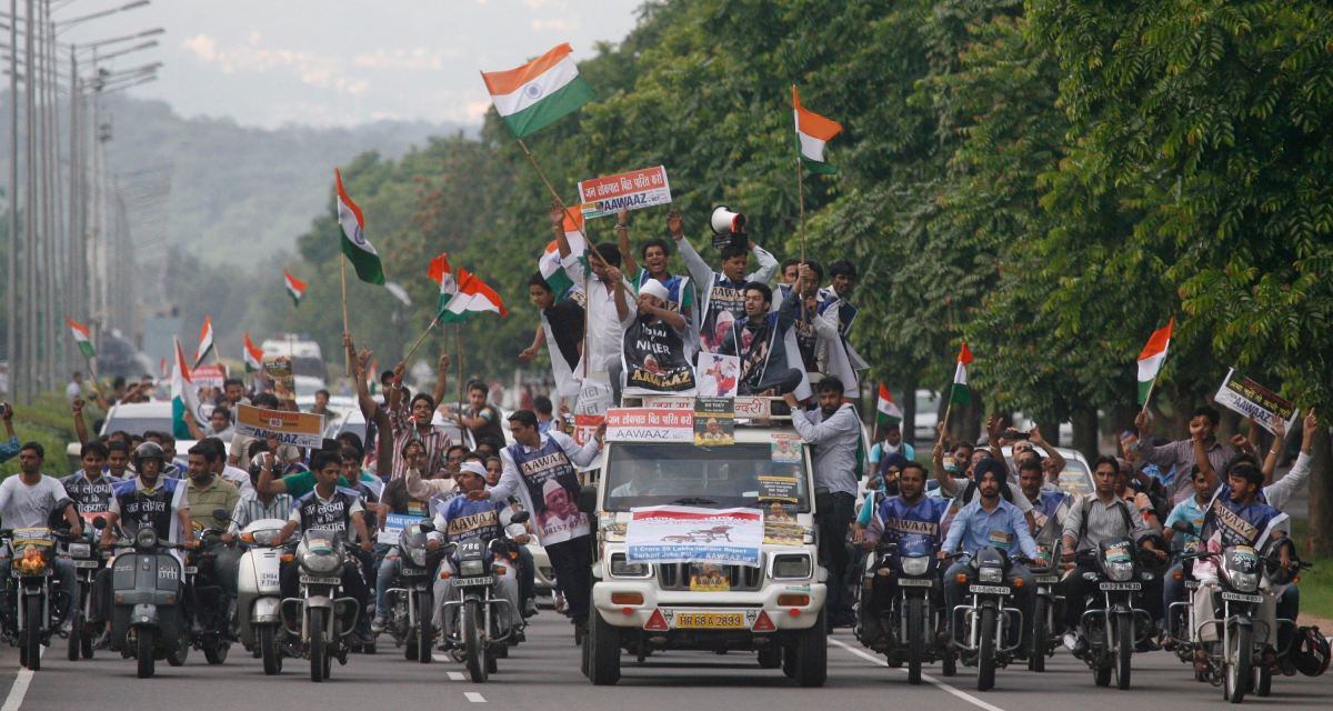 With the national flag in hand supporters of Anna Hazare rally down a road on their bikes and vehicles in Chandigarh