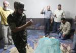Men take pictures of Muammar Gaddafi's corpse displayed at a house in Misrata