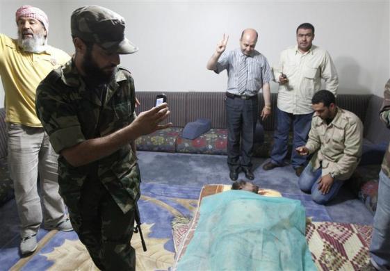 Men take pictures of Muammar Gaddafi's corpse displayed at a house in Misrata