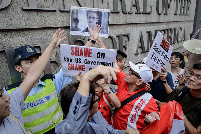 Protesters shout slogans as they hold up a picture of former US spy Edward Snowden in front of the US consulate in Hong Kong on June 13, 2013.  Snowden broke his silence on June 12, vowing to fight any bid to extradite him from Hong Kong and accusing Washington's cyber-troops of prying into hundreds of thousands of targets globally including many in China.  AFP PHOTO / Philippe Lopez
