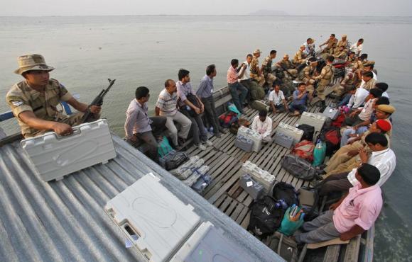 Polling officers with electronic voting machines (EVM) along with Indian security personnel travel in a boat to reach polling stations ahead of the sixth phase of the general election in Assam April 23, 2014. REUTERS/Utpal Baruah