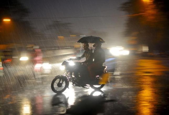 Men ride on a motorbike through a busy road.